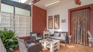 Un patio al aire libre con mobiliario de mimbre, una mesa blanca y una valla decorativa.