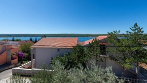 Ein Küstenwohngebiet mit Häusern mit Terrakotta-Dächern, einem klaren blauen Himmel und Blick auf das Meer.