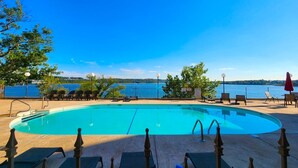 Une piscine avec des chaises longues et vue sur un lac.