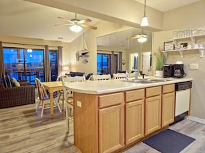 A modern kitchen with a large island, dining area with a view, and a cozy seating area.