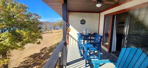 A covered porch with blue Adirondack chairs, a table, and a lantern. - Amazing Lake Views ~ 2 Kings ~ Outdoor Pool (Kimberling City)