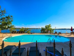A swimming pool with lounge chairs and a view of a lake.