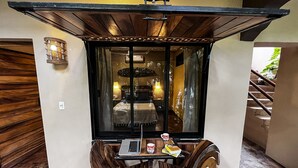 A cozy room with a wooden ceiling, a bed with a canopy, a small table with a laptop, and a chair.