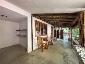 A room with a wooden table and chairs, a window with a wooden frame, and a thatched roof structure. - Hotel Gallo de Mar (Puerto Escondido)
