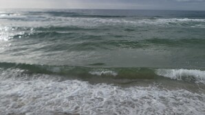 Uma praia com ondas e um céu nublado.