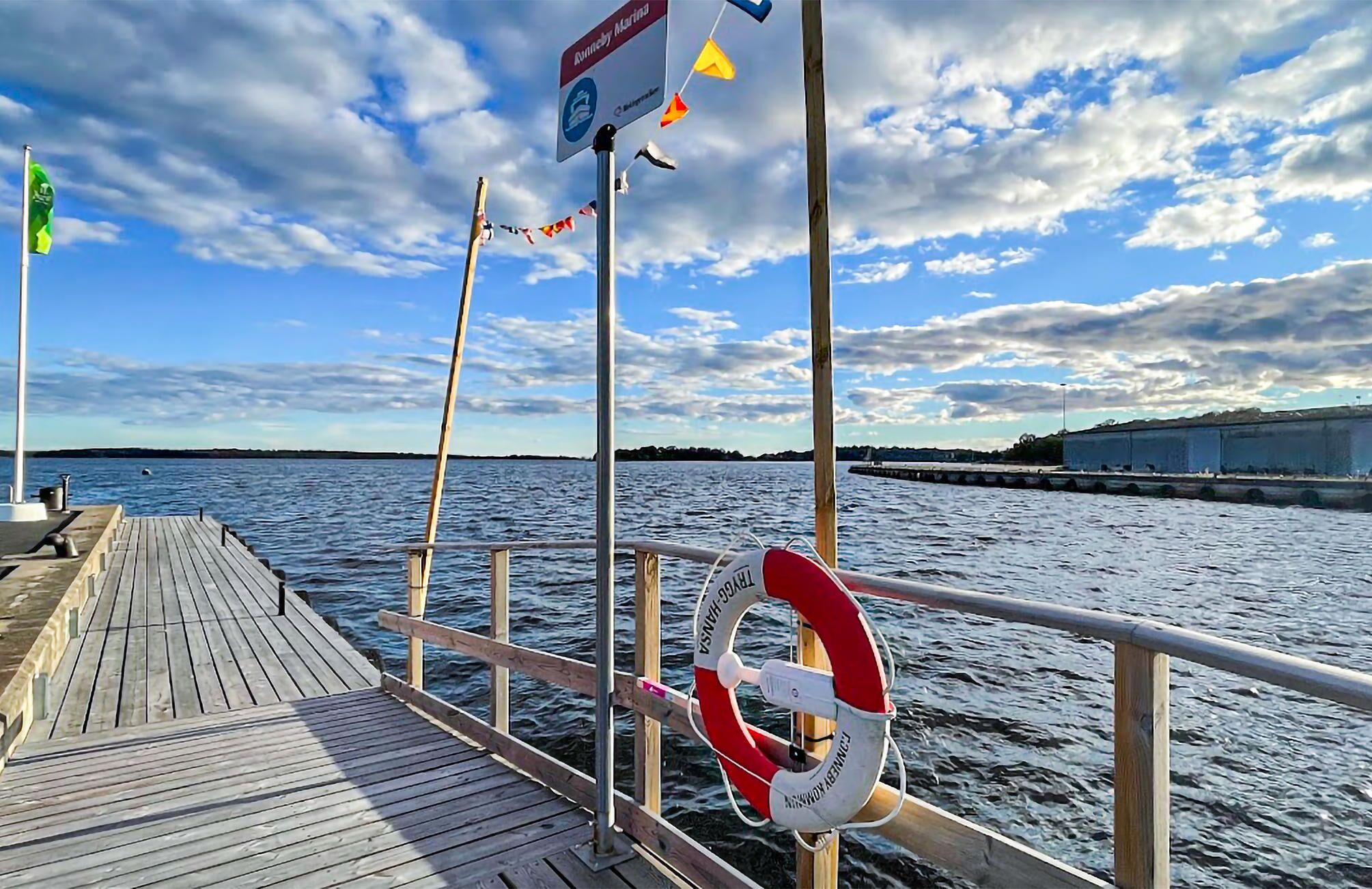 Un muelle de madera que se adentra en el agua, con un flotador anclado a la barandilla.