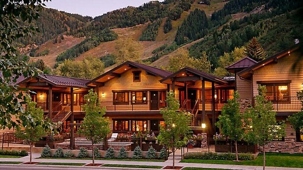 A row of log cabin-style buildings with multiple stories, balconies, and a mountainous backdrop.