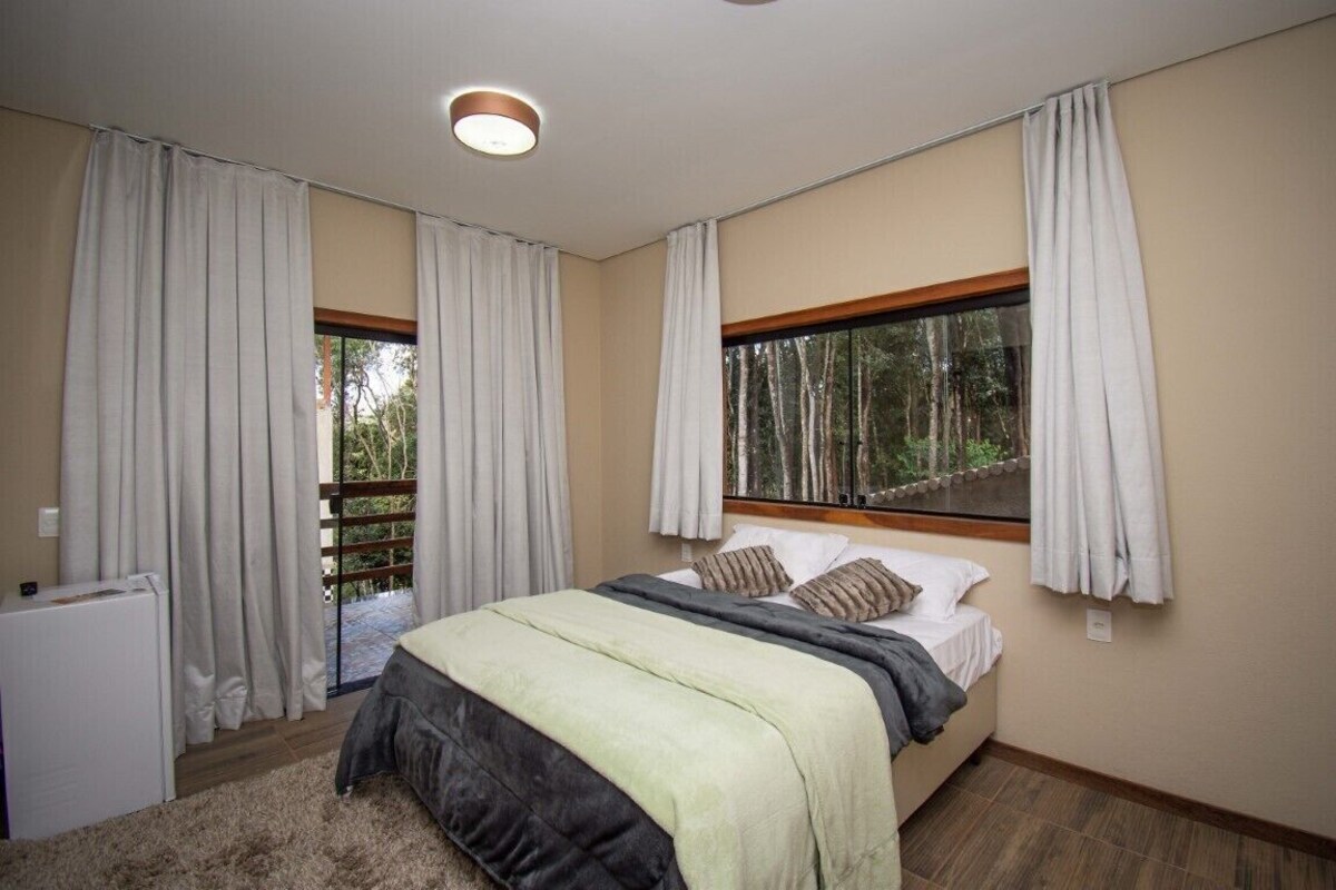 Un dormitorio con cama, cortinas, ventana y radiador.