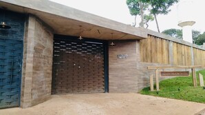 A building entrance with a large brick wall and a wooden fence. - Pousada Evolução engenho (Nova Lima)