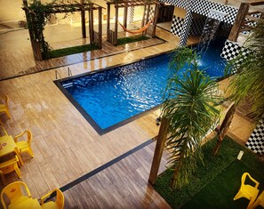 Relax by the clear pool surrounded by a seating area and lush greenery.