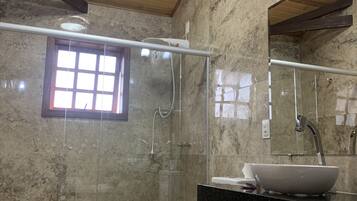 Un baño con pared de mármol, inodoro, lavamanos, ducha y ventana.