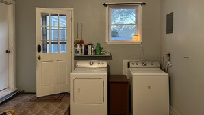 A laundry room with two washers and dryers, a window, and a door. - Cozy home with easy access to the main highway thru town, but in quiet area.  (Laverne)