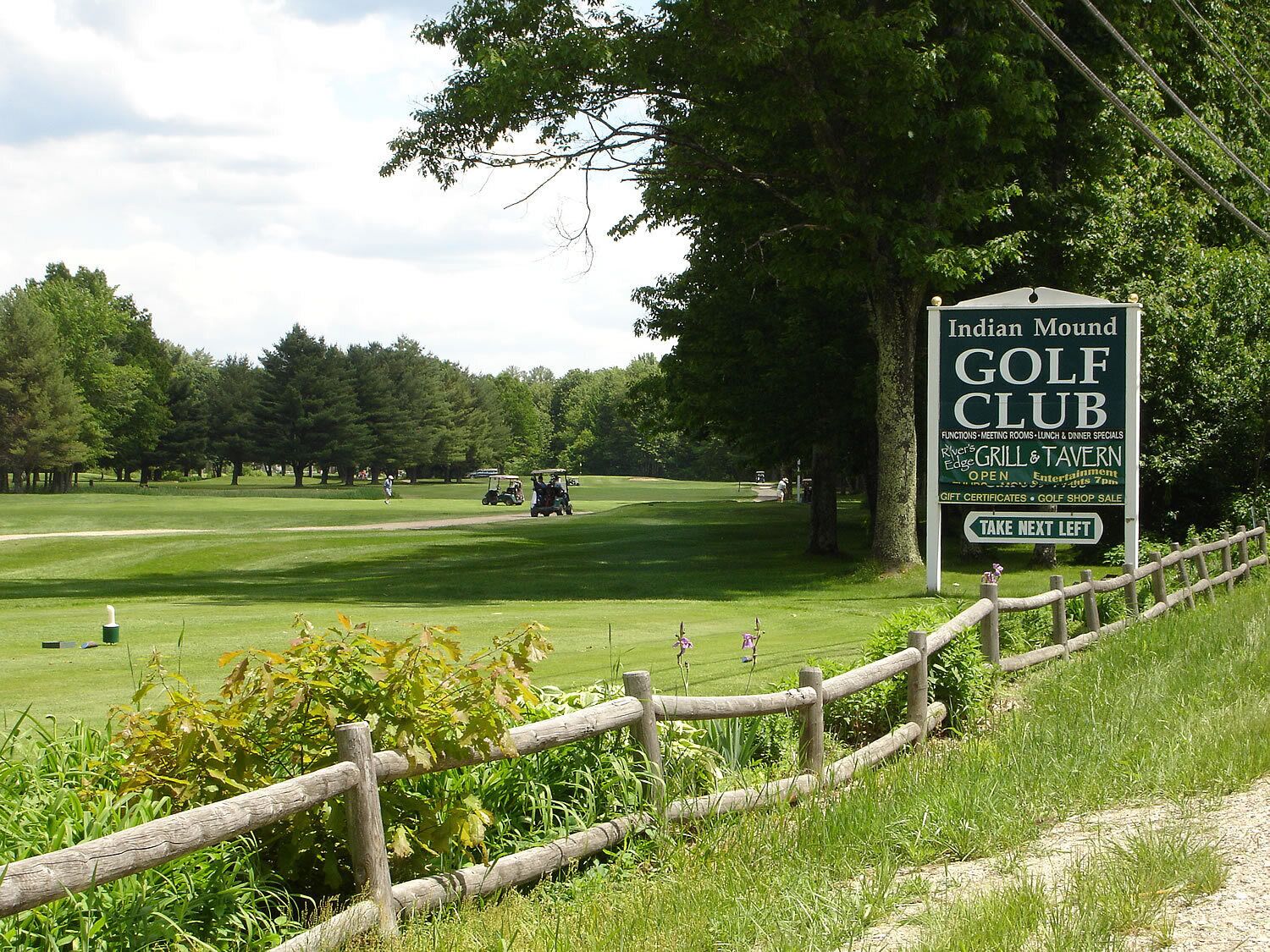 Un parcours de golf avec un panneau indiquant le « Indian Mound Golf Club », et précisant les commodités disponibles, comme un restaurant et un bar.