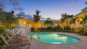A pool area with lounge chairs, a staircase, and a building with balconies. - Beach Club Cute Cottage in C Bldg (Siesta Key)