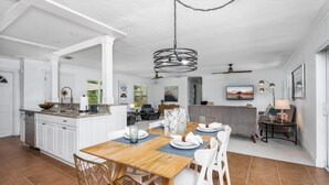 Uma cozinha moderna com armários brancos, uma mesa de jantar de madeira e um lustre.