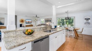 Uma cozinha espaçosa com bancadas de granito, lava-louças e uma área de refeições com mesa e cadeiras.