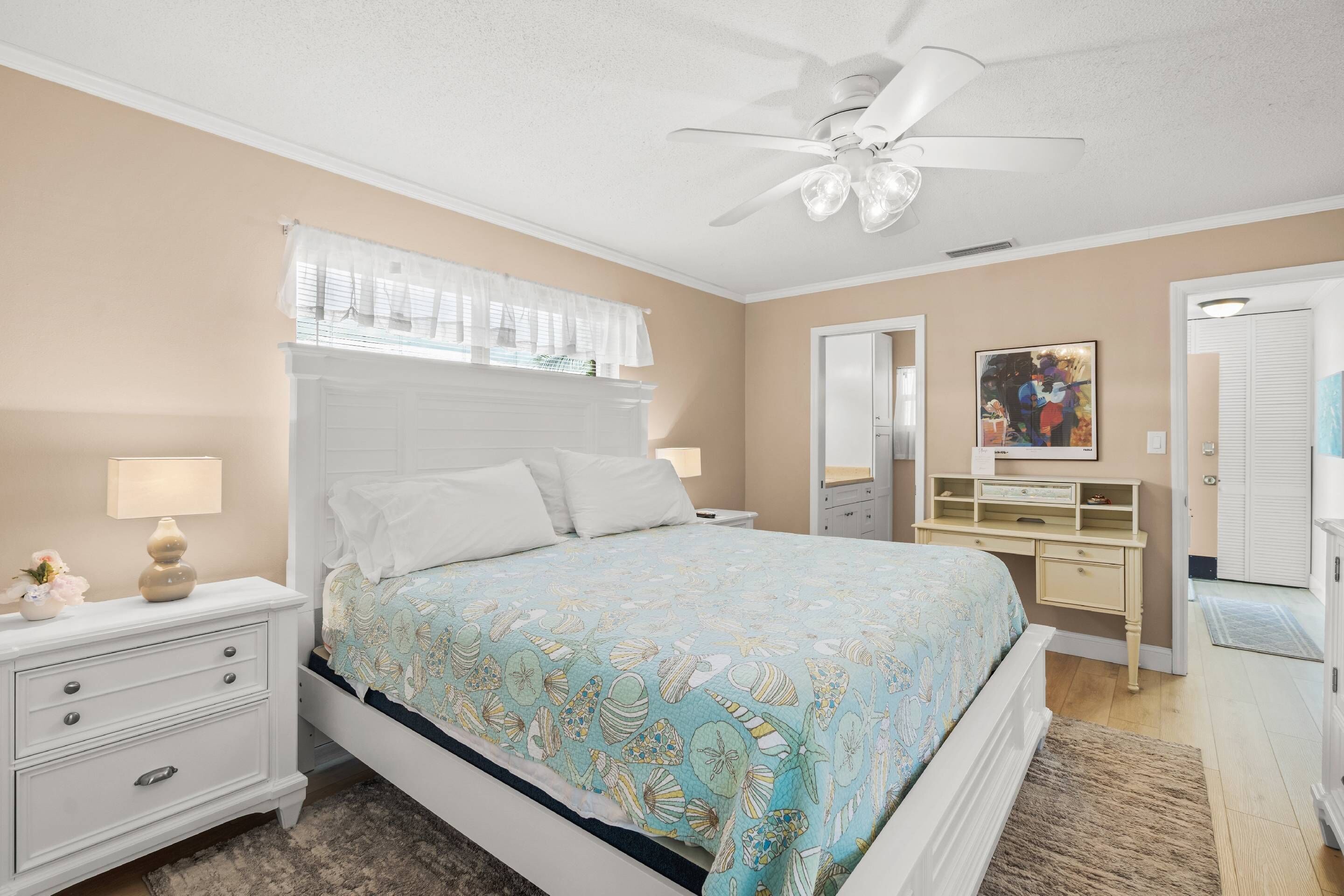 A bedroom with a bed, nightstand, dresser, and a ceiling fan.