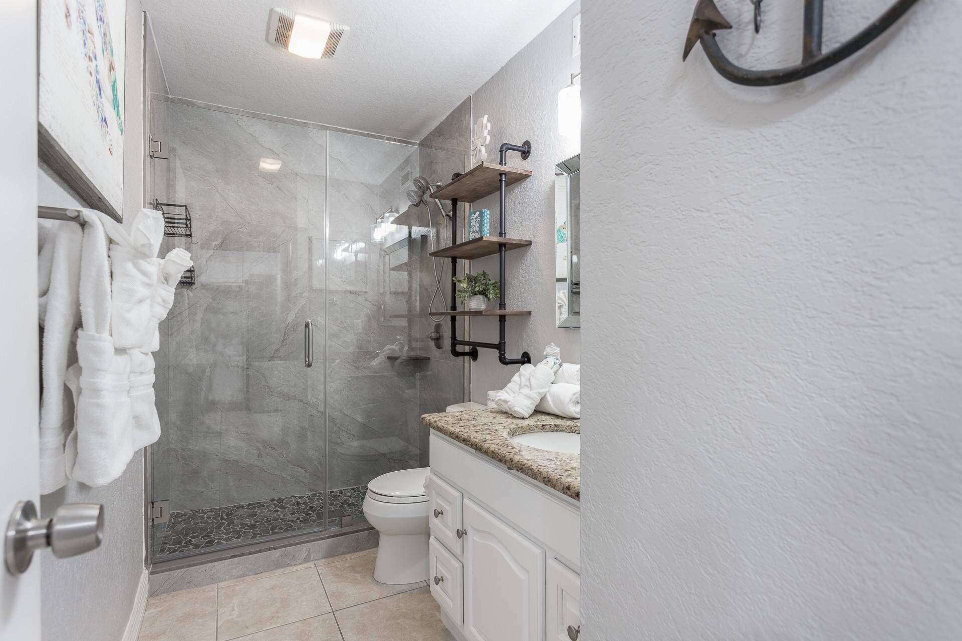 Un baño moderno con cabina de ducha de vidrio, inodoro y tocador con lavabo.