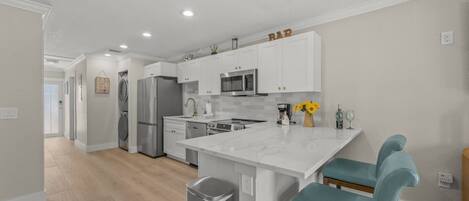 A modern kitchen with white cabinets, stainless steel appliances, and a central island with bar stools.