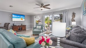 A living room with a TV, sofas, a coffee table, and a ceiling fan. - Minorga on the Gulf (Siesta Key)