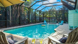 Ein Poolbereich mit Glasveranda, Liegestühlen und einem Tisch mit Getränken.
