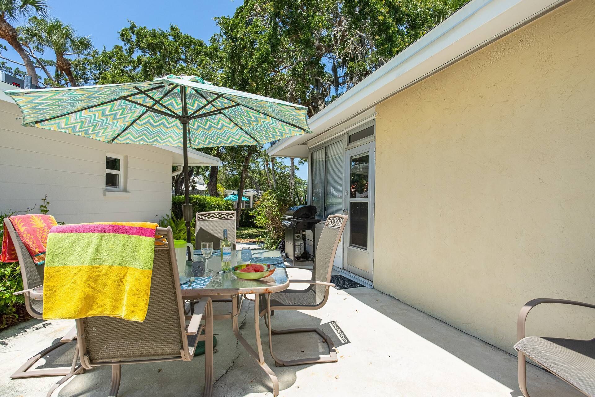 An outdoor patio with a table, chairs, and a grill.