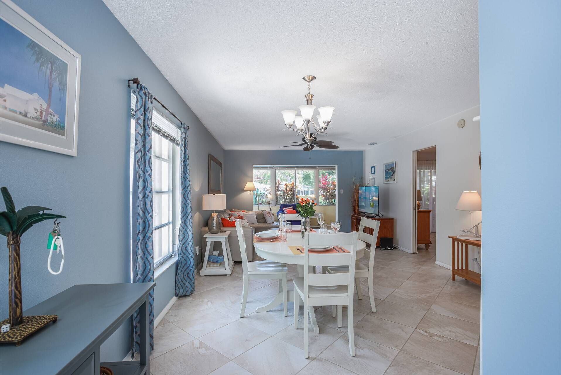 A dining area with a round table, white chairs, and a ceiling fan.