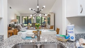 A modern kitchen with granite countertops, a stainless steel sink, and a dining area with a central island. - Yellow Pine Villa (Sarasota)