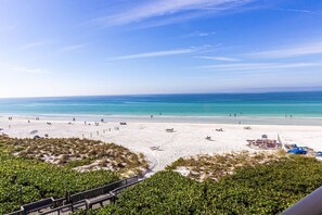 A beach with white sand, clear blue water, and sparse vegetation. - Siesta Breakers on Crescent Beach (Siesta Key)