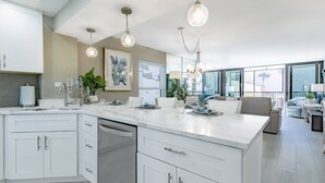 A modern kitchen with white cabinetry, a built-in dishwasher, and pendant lighting.