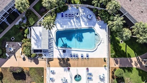 Vue aérienne d’un hôtel doté d’une grande piscine, de plusieurs espaces de détente et d’un environnement verdoyant.