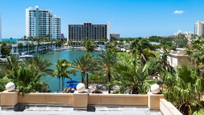 A waterfront hotel with a marina, palm trees, and high-rise buildings in the background. - Beach Club Modern Condo C Bldg (Siesta Key)
