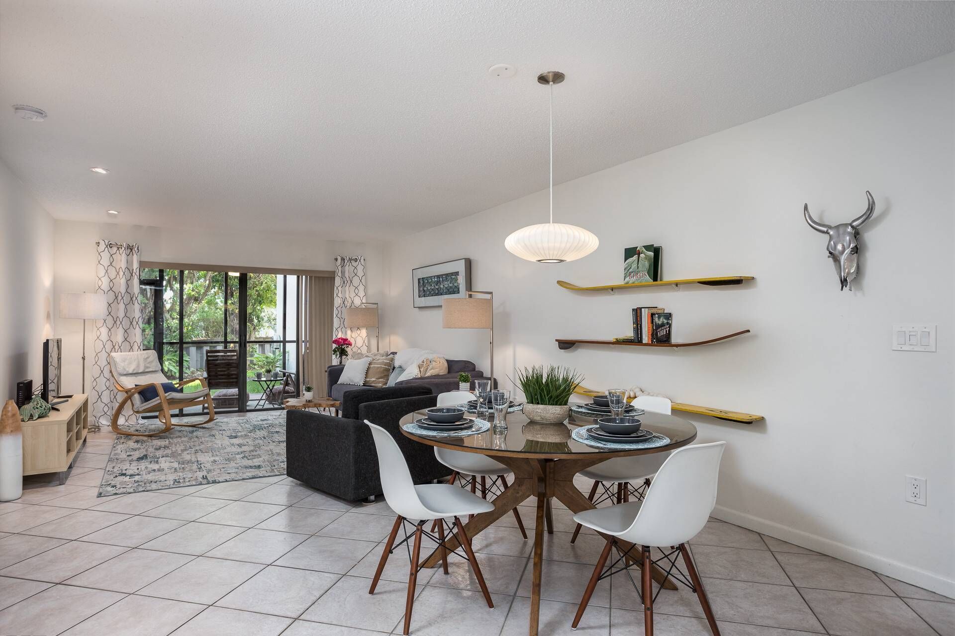 A modern living room with a dining area, large windows, and a bull skull decoration.