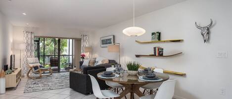 A modern living room with a dining area, large windows, and a bull skull decoration.