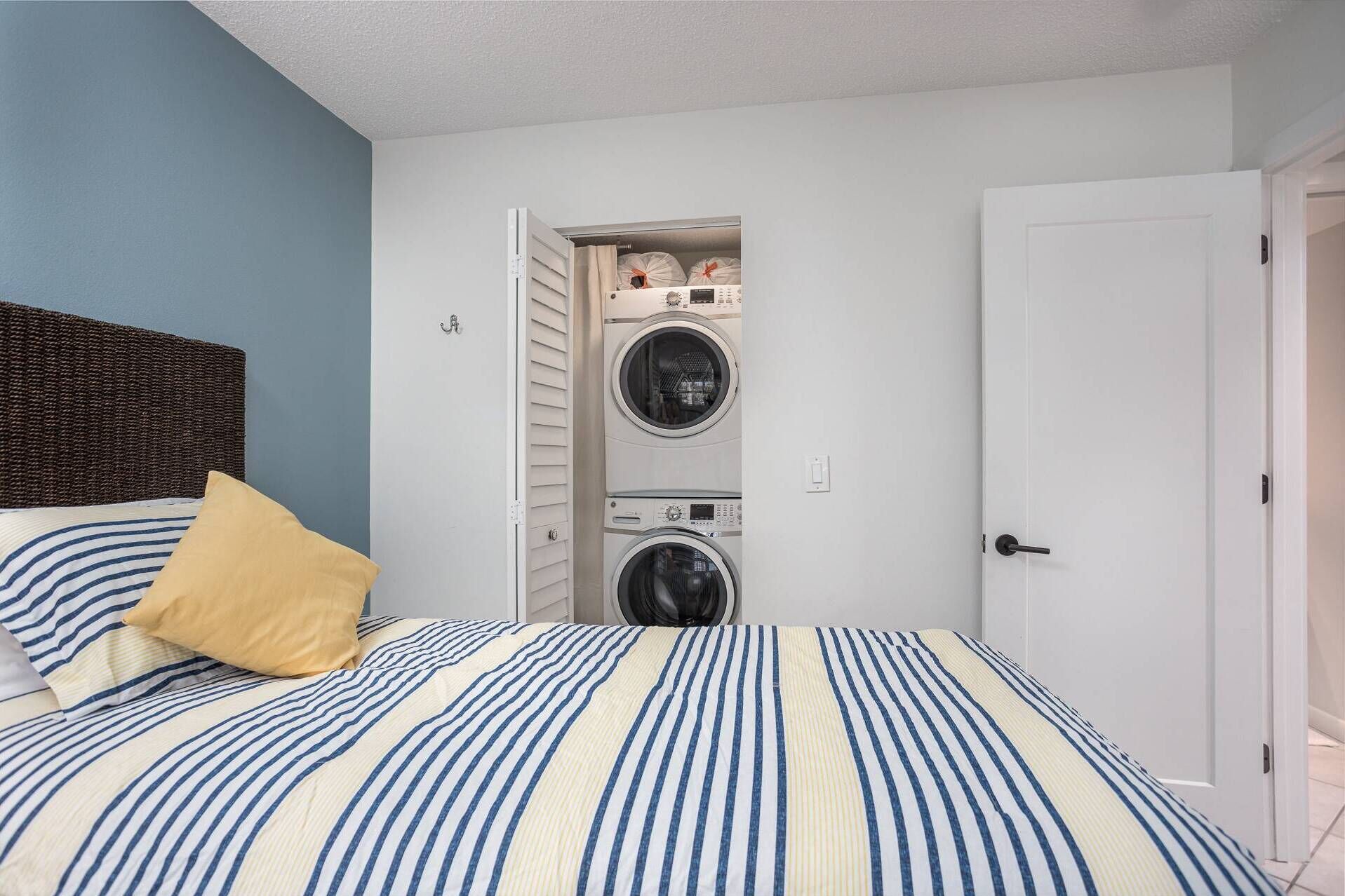 A bedroom with a bed, a washing machine, and a door.