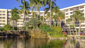 A hotel with a pool, palm trees, and a waterfall. - Harbor Towers 4th Fl Pool & Bay Views End Unit (Siesta Key)