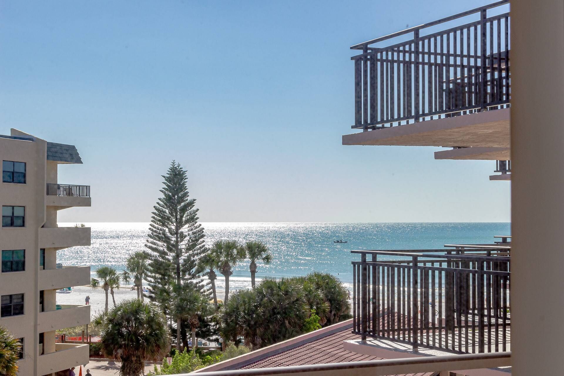 A balcony with a view of the ocean and palm trees.