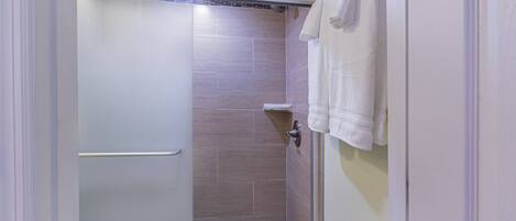Un baño moderno con ducha, paredes de azulejos, un perchero para toallas y un dispensador de papel higiénico.