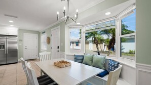 A kitchen with a white table, chairs, and a chandelier. - Crystal Sands & Seahorses Beach Villa (Siesta Key)