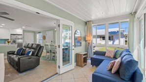 A spacious living area with a blue sofa, a leather chair, and a dining table. - Crystal Sands & Seahorses Beach Villa (Siesta Key)