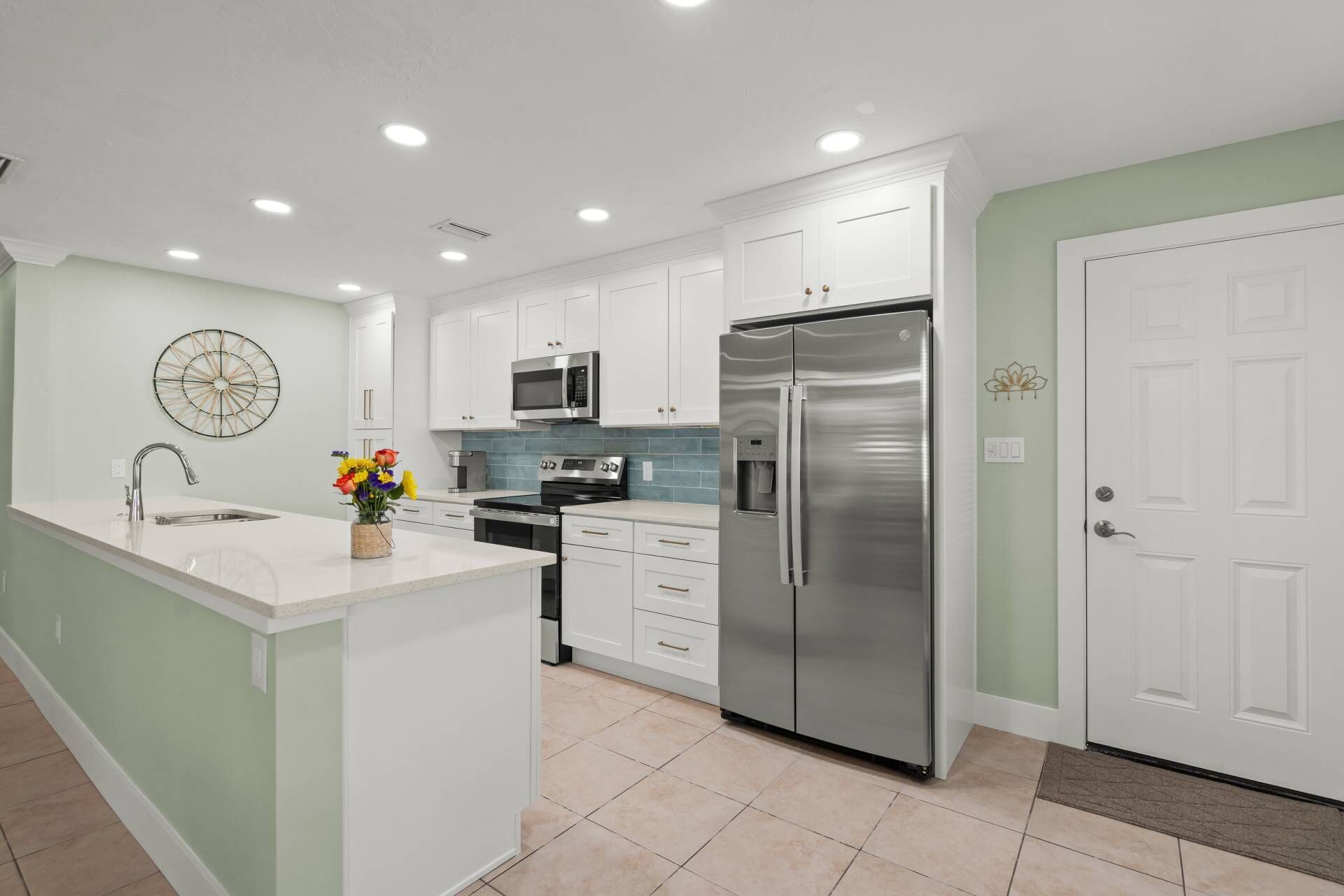 A modern kitchen with white cabinets, stainless steel appliances, and a central island.