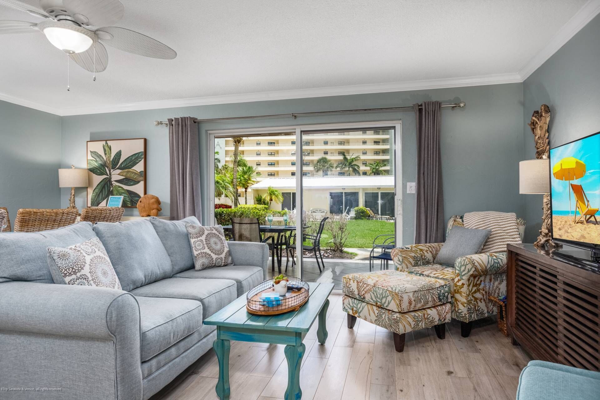 A living room with a grey sofa, a patterned armchair, a wooden coffee table, and a television.