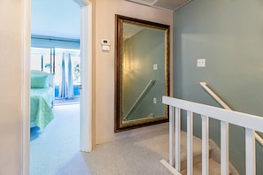 Enjoy a room with a balcony offering a view of the outside, featuring a large mirror, carpeted floor, and white railing.
