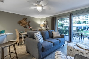Relax in this stylish living room with a sofa, ottoman, and wicker chair, perfect for unwinding with a view.