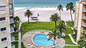 A pool surrounded by a white fence, with a beach and palm trees in the background. - Jamaica Royale Townhome #2 - Steps From Beach (Siesta Key)