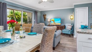 A dining area with a table set for two, a television, and a ceiling fan. - Jamaica Royale Townhome #2 - Steps From Beach (Siesta Key)