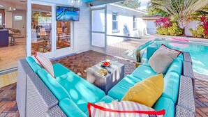 Ein Außenbereich mit einer Terrasse, einem blauen Sofa, einem kleinen Tisch mit einem Glas und einem Pool.