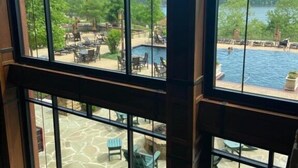 A room with large windows overlooking a pool area with outdoor seating and a stone patio.