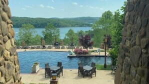 A stone-framed outdoor area with a pool, lounge chairs, and a view of a lake and hills.