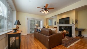 Una sala de estar con chimenea, ventilador de techo y televisor.